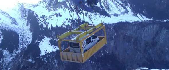 Lieferwagen wird an einem Kran über eine Winterlandschaft gehoben
